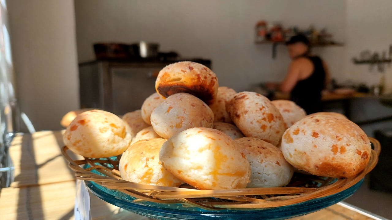 Freshly baked Brazilian cheese bread on a plate in a warm, inviting kitchen setting.